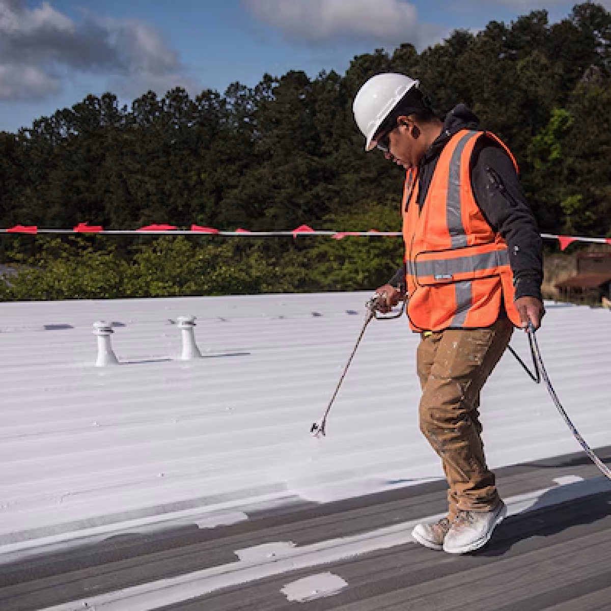 Roofing contractor applying a protective coating to a commercial metal roof