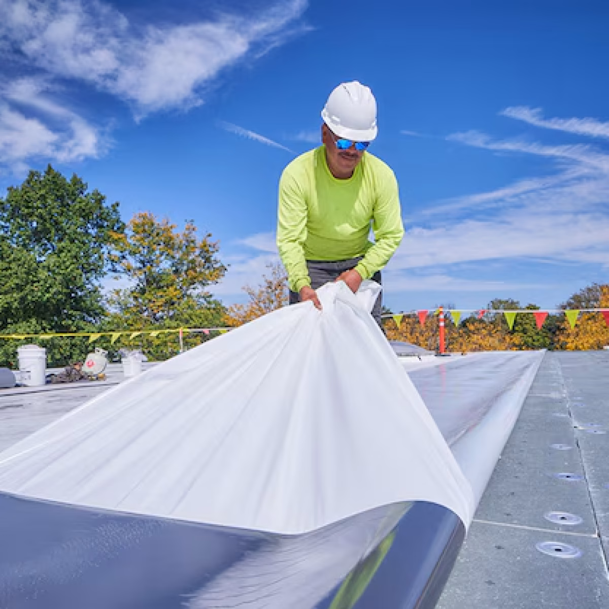 Roofing contractor installing a white TPO membrane on a commercial roof
